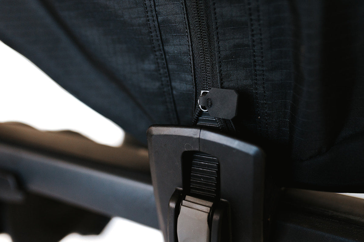 Rack ratchet strap passing through a reinforced pass-through on the cover's wheel section
