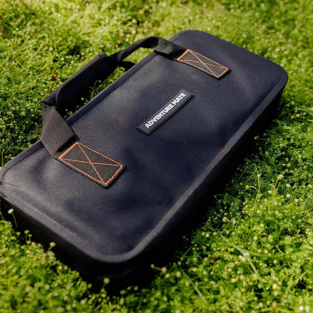 Black Adventure Mate zippered carry case with orange stitching resting on grass