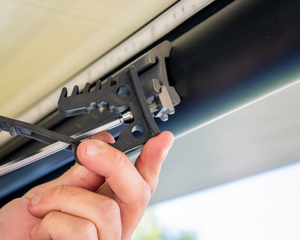 Tightening an L-track nut bolt with a hex driver under a camper roof