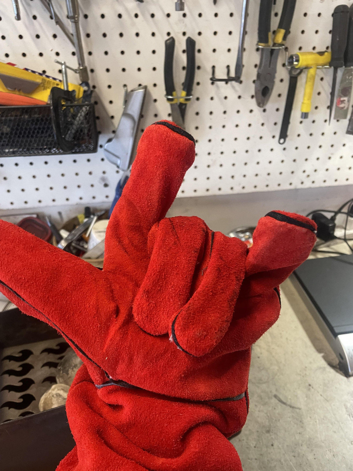 Close-up of a red leather fireproof glove in a workshop setting