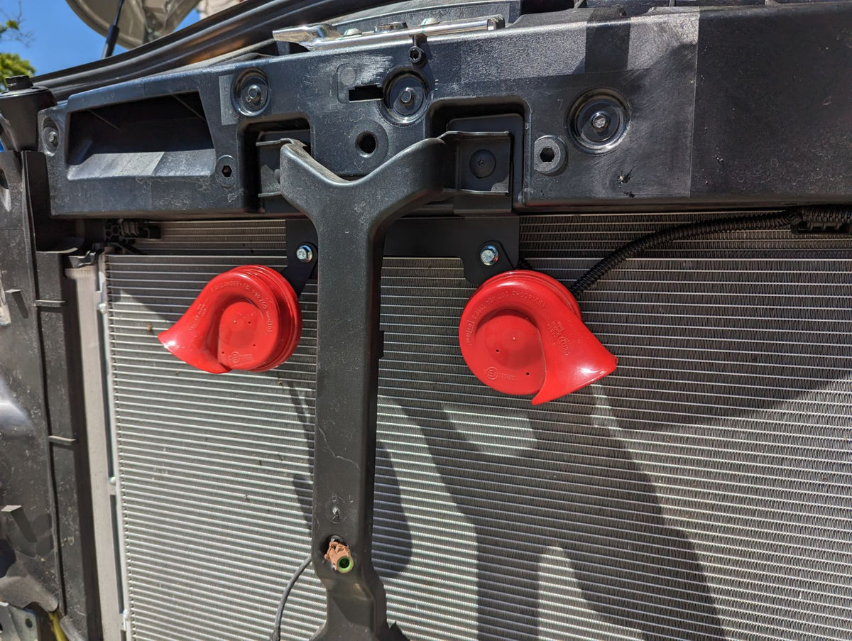 Red horns mounted on a black bracket in front of a radiator