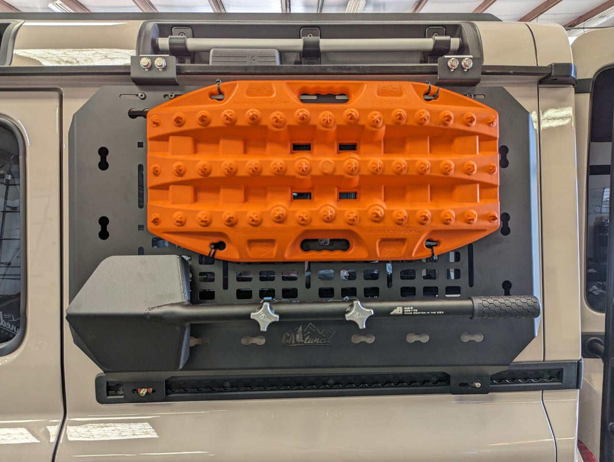 Orange recovery boards strapped to the MOLLE panel on the side of an SUV