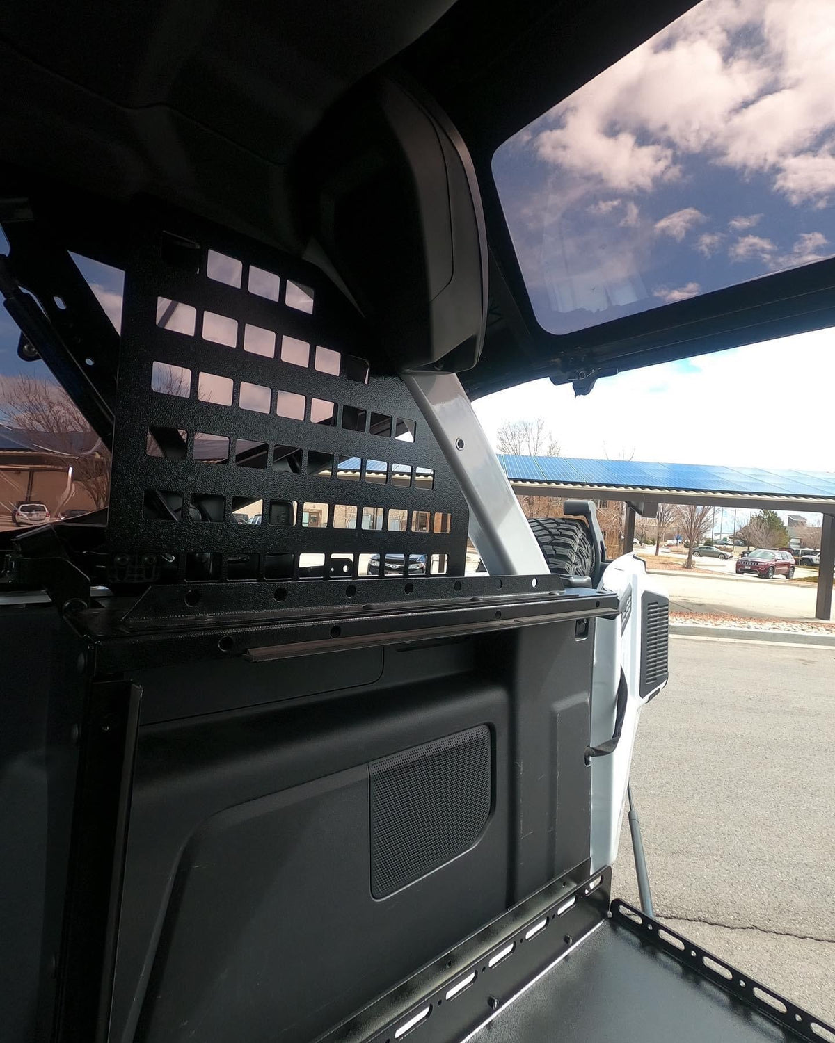 Roll bar MOLLE panel above the Slipstream in a white Bronco, sky through the window