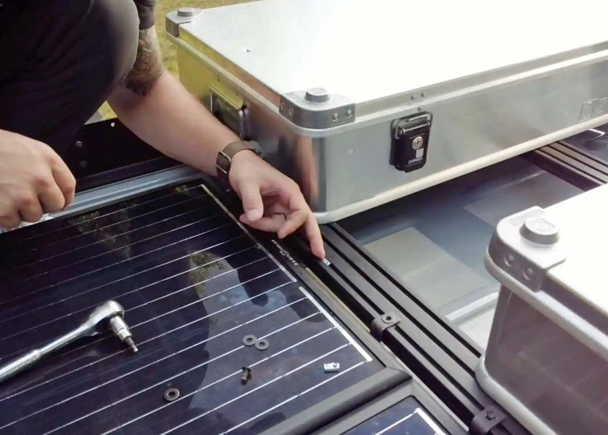 Installing an accessory onto a DRIFTR roof rack extrusion using the sliding T-nut hardware, with storage boxes mounted on the rack