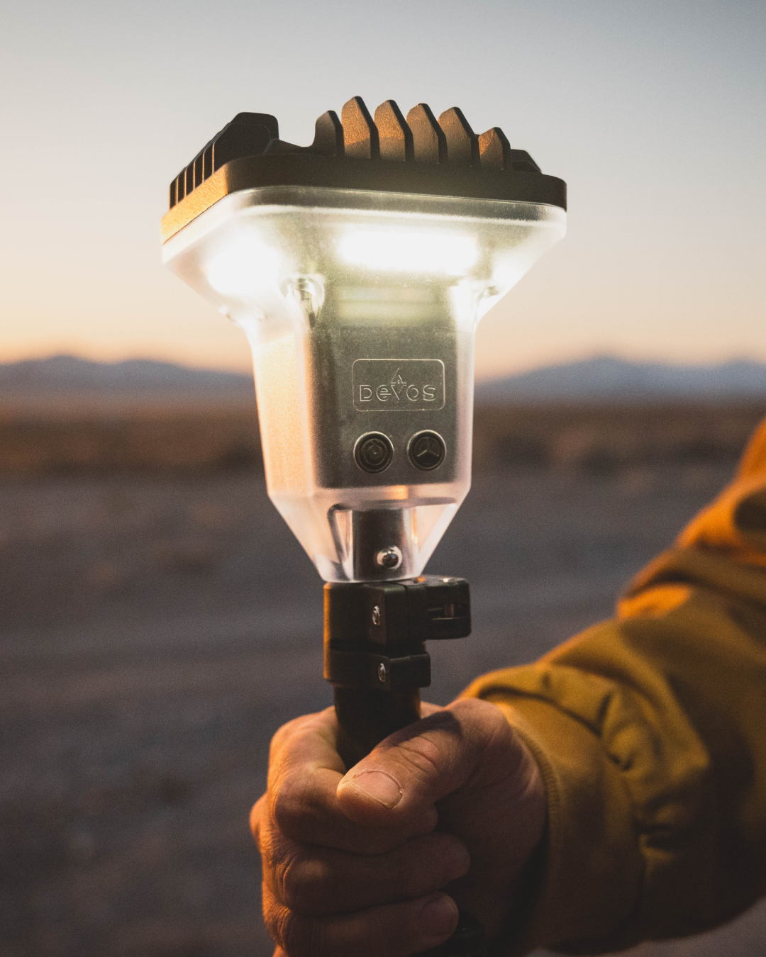 Hand holding a portable light source with a desert landscape in the background