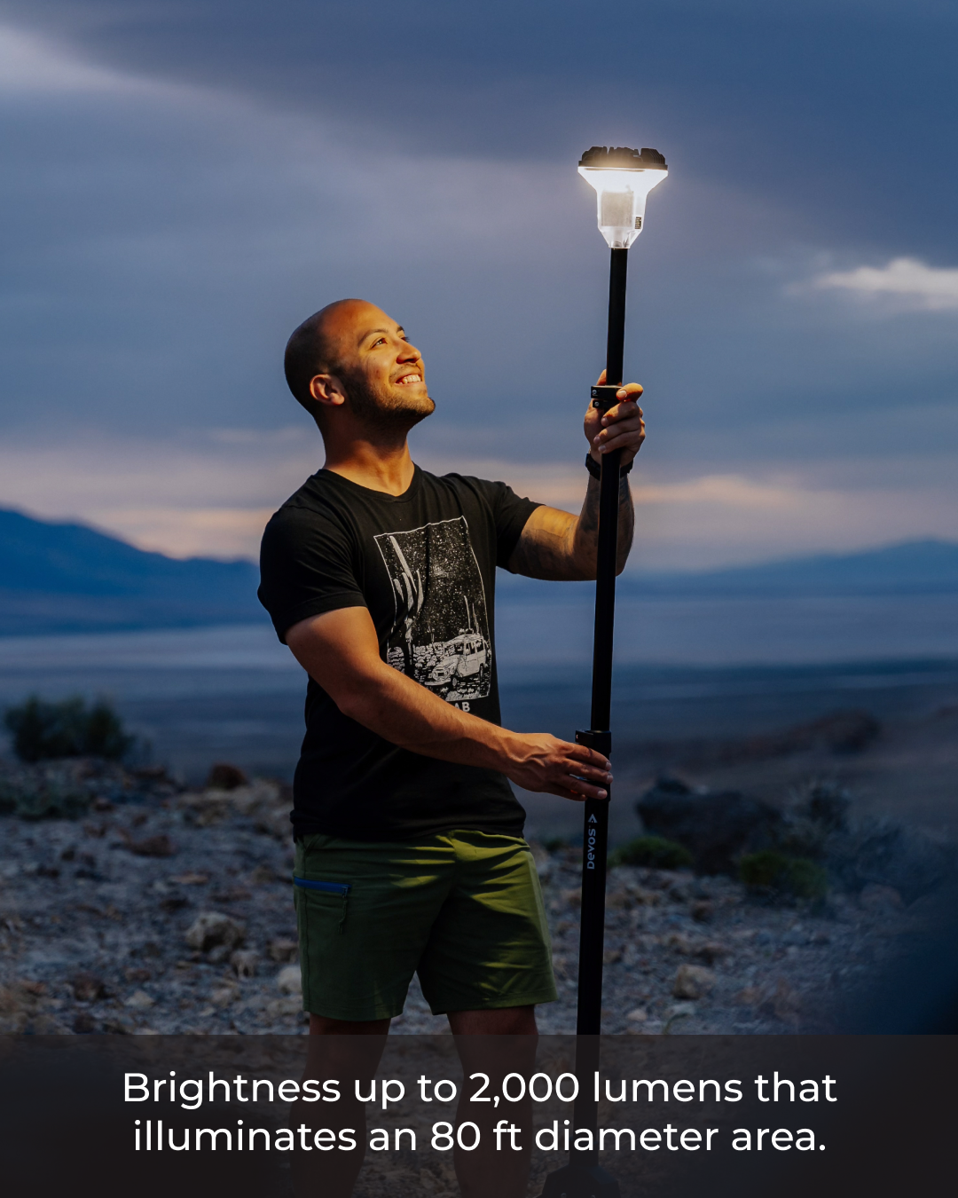Person holding a solar lamp in a desert landscape with text about brightness and area illumination.