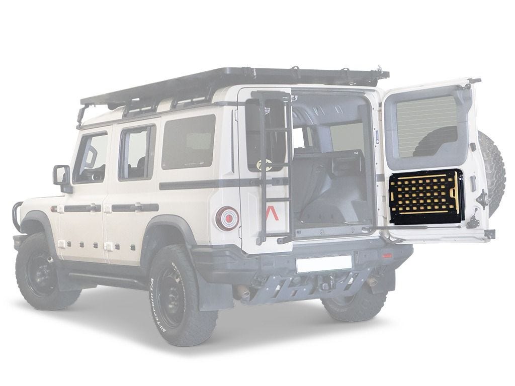 Rear three-quarter view of a white Ineos Grenadier with the Front Runner drop down tailgate table closed on the rear swing door, Molle panel facing out